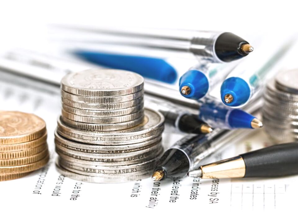 Stacks of coins beside pens and paperwork