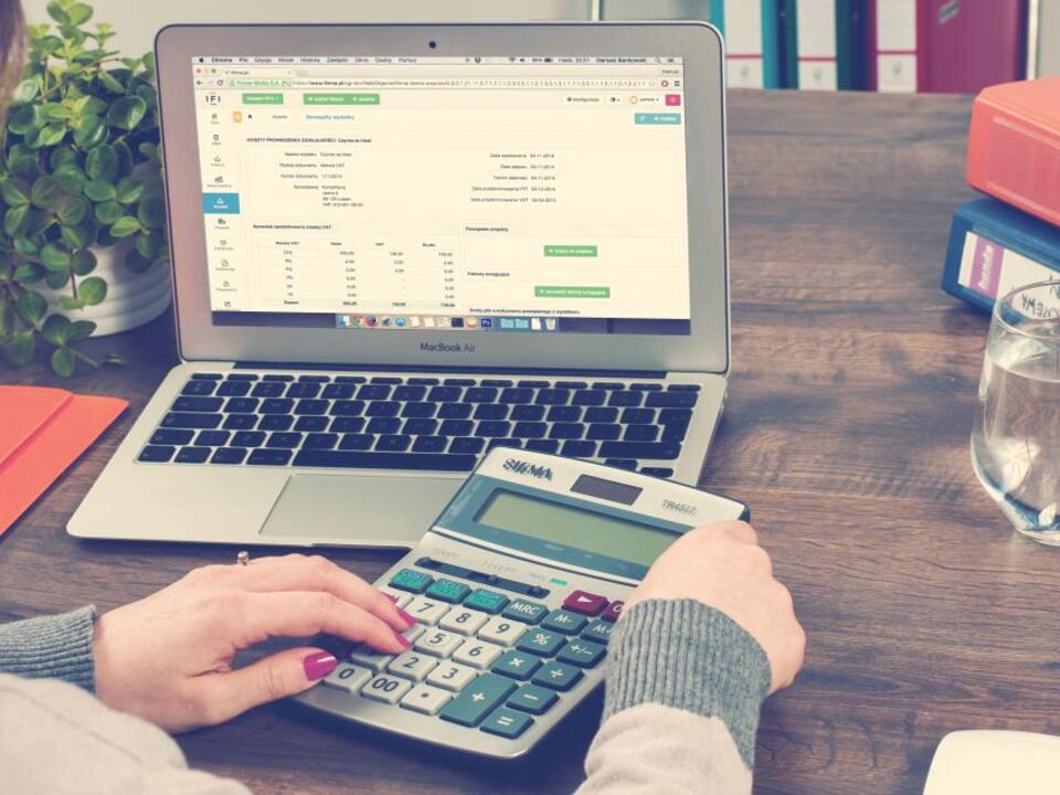 Someone working through numbers with a calculator and laptop