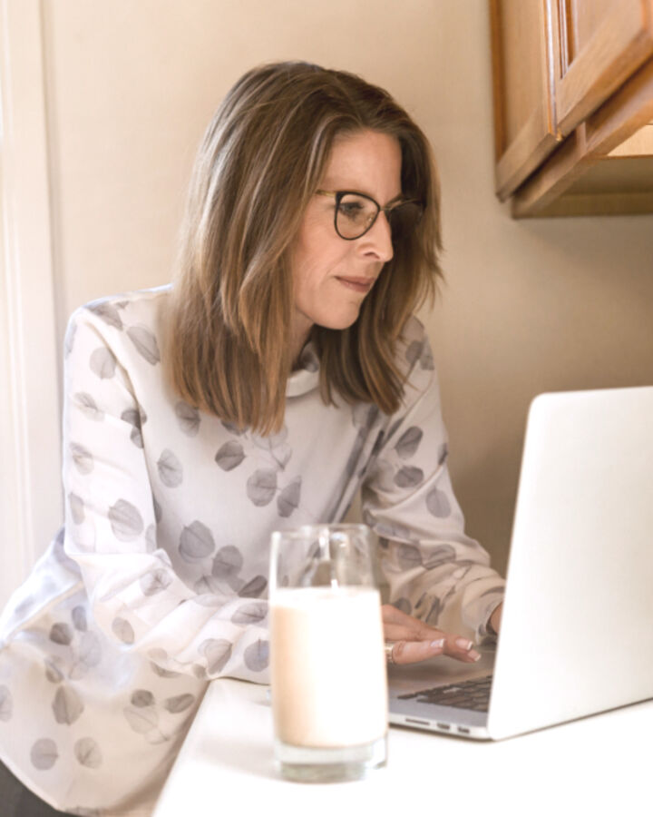 A woman checking her laptop at the kitchen counter
